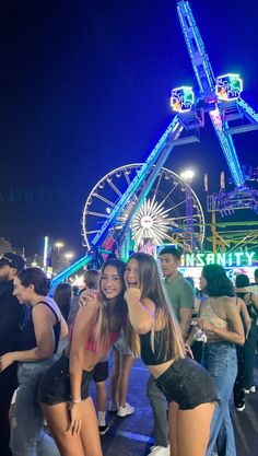 two girls standing next to each other in front of a ferris wheel at an amusement park