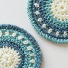 two crocheted coasters sitting on top of a table