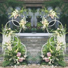 two metal archways with flowers and greenery in front of an outdoor wedding ceremony