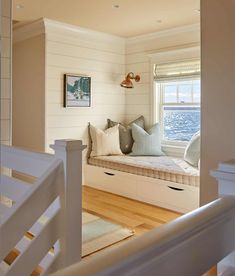 a window seat in the corner of a room with wooden flooring and white walls