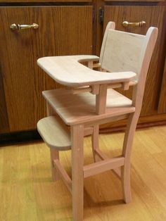 a wooden high chair sitting on top of a hard wood floor next to a counter