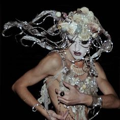 a woman with her hair blowing in the wind and pearls on her face, holding a cell phone