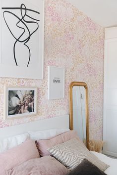 a bedroom with pink and gold wallpaper and pictures on the wall above the bed