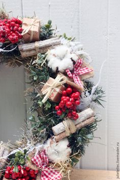 a christmas wreath with red berries, cotton and cinnamons on it is hung in front of a door