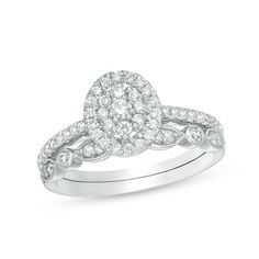 a white gold ring with diamonds on the band and an oval shaped diamond in the center