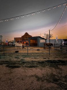 a barn with lights strung over it and horses grazing in the field at night time