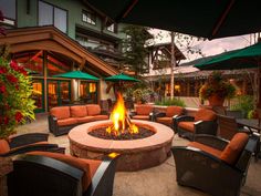 an outdoor fire pit surrounded by chairs and umbrellas