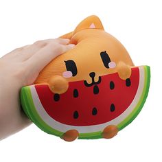 a hand holding a watermelon shaped toy with a cat on it's face