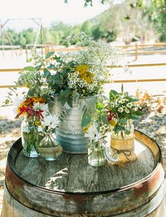 several vases filled with flowers sitting on top of a barrel