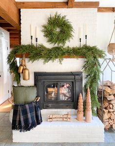 a fireplace decorated for christmas with pine cones and wreaths