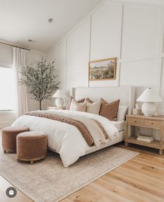 a bedroom with white walls and wood flooring has a large bed in the center