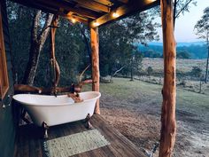 a bath tub sitting on top of a wooden floor next to a tree filled field