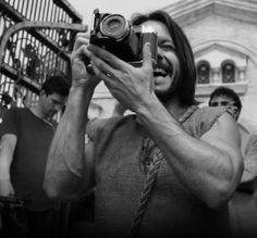 a man is holding up a camera in front of some other people on the street