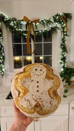 a person holding up a pastry in front of a christmas wreath on the kitchen counter