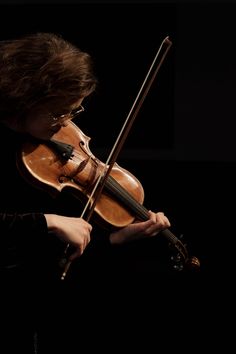 a woman is playing the violin with her hands