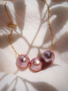 *Limited Edition* An unfailing new classic. This Triple Edison Floating Pearl Necklace is a steadfast companion. Seemingly plucked straight from the ocean, three near round pink pearls flutter along a delicate gold filled chain. This piece is striking solo or makes a bold statement layered with with a bevy of other beauties.✦ CHOOSE YOUR ADJUSTABLE LENGTH ✦✦ DETAILS ✦✧ Name: Lokelani (LOE keh LAH nee) - heavenly rose.✧ Three Large 12mm-13mm Natural Mauve Edison Pearl✧ Color will vary slightly. ✧ Formal Pink High Luster Necklace, Pink Akoya Pearl Necklaces With Round Beads, Pink Akoya Pearl Round Bead Necklace, Luxury Pink Necklace With Pearl Pendant, Pink Akoya Pearl Single Strand Necklace, Luxury Pink Pearl Necklace, Elegant Pink Pearl Necklace With Pendant, Luxury Pink Pearl Necklace For Wedding, Formal Pink Akoya Pearl Necklace