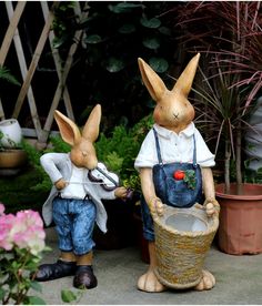 two statues of rabbits in overalls and aprons, one is holding a basket