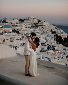 a bride and groom embracing on the roof of a building in oia, greece