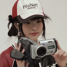 a woman holding a camera and wearing a hat