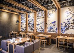 an empty restaurant with blue and white paintings on the walls, wooden tables and chairs