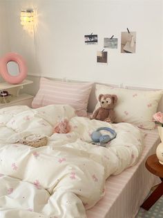 a teddy bear sitting on top of a bed with white sheets and pink striped pillows