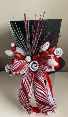 a red and white striped bow with candy canes on the top is attached to a black hat