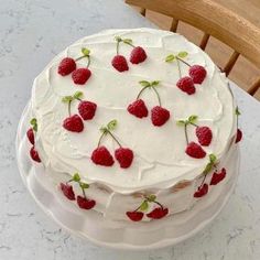 a cake with white frosting and raspberries on it sitting on a table