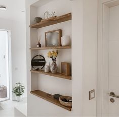 the shelves are filled with vases and other decorative items on top of them in this white room