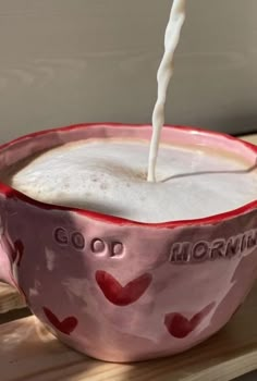 a red and white bowl filled with milk being poured into it's drinker