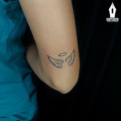 a woman's arm with a tattoo on it that has an angel wing in the middle