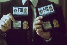 two men in suits holding up their id badges