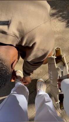 a man with his foot on the ground near someone's feet wearing white shoes