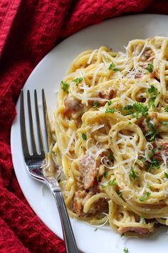 a white plate topped with pasta covered in sauce and parsley next to a fork