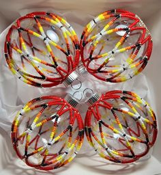 four red, yellow and black beaded bracelets in a white box with string