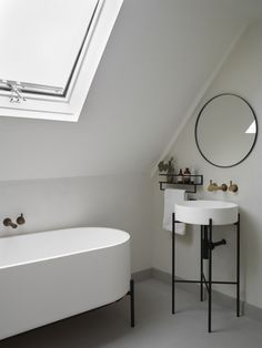 a white bath tub sitting under a bathroom window next to a sink and a mirror