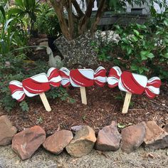 four red and white candy canes sitting on top of each other in front of some rocks