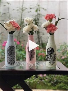 three vases with flowers in them sitting on a table