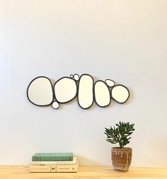 three oval mirrors mounted on the wall above a potted plant next to a bookshelf