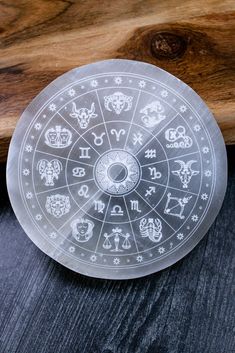 the zodiac sign is etched into an acrylic glass plate on a wooden surface