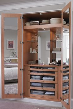 an open closet with lots of drawers and towels on the shelves in front of it