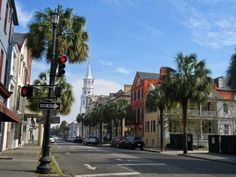 a street with palm trees on both sides and a church steeple in the background