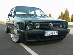 a black vw golf wagon parked in a parking lot with its hood up and lights on