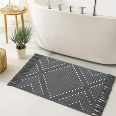 a bath tub sitting next to a rug on top of a white floor in a bathroom