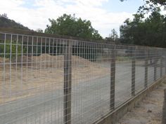 a fenced in area with dirt and trees