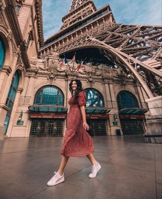 a woman walking in front of the eiffel tower