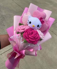 a hello kitty crochet bouquet with pink roses and teddy bears in it is held by someone's hand