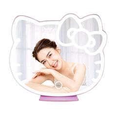 a woman is posing in front of a hello kitty shaped mirror with her hand on her chin