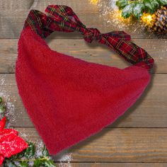 a red hat with a plaid bow on top of it next to holly wreaths