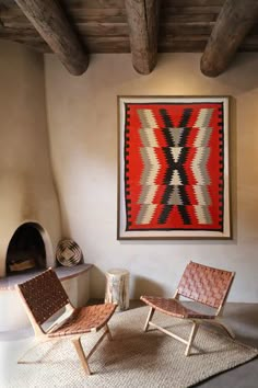 two chairs and a rug in front of a wall with a painting hanging on it