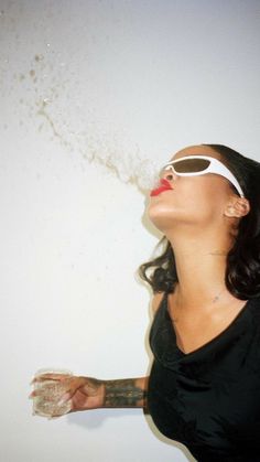 a woman with her eyes closed is blowing sand into the air while wearing sun glasses